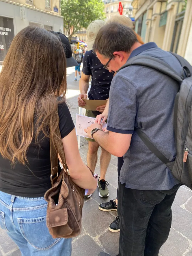 Joueurs résolvant une énigme lors d'un jeu de piste INDY GAMES dans une rue de Paris