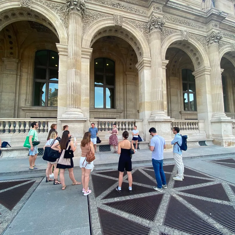 Équipe écoutant les consignes d'un jeu de piste team building devant le Louvre à Paris