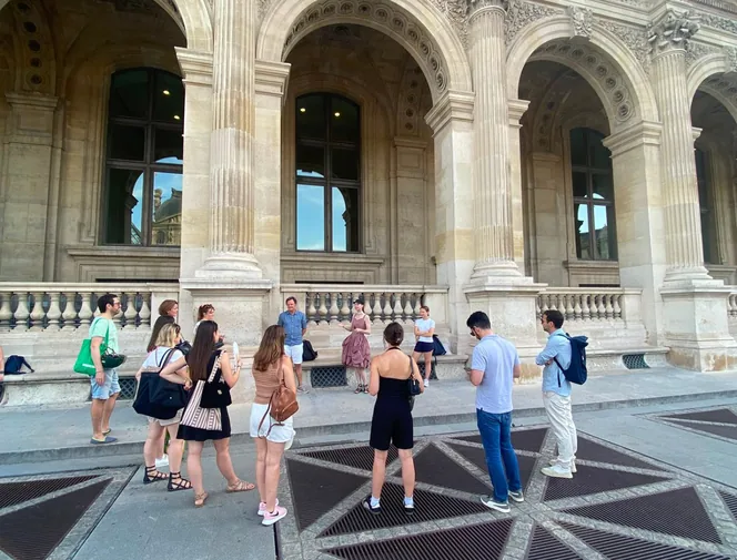 Équipe de collaborateurs en team building devant les arcades du Louvre à Paris